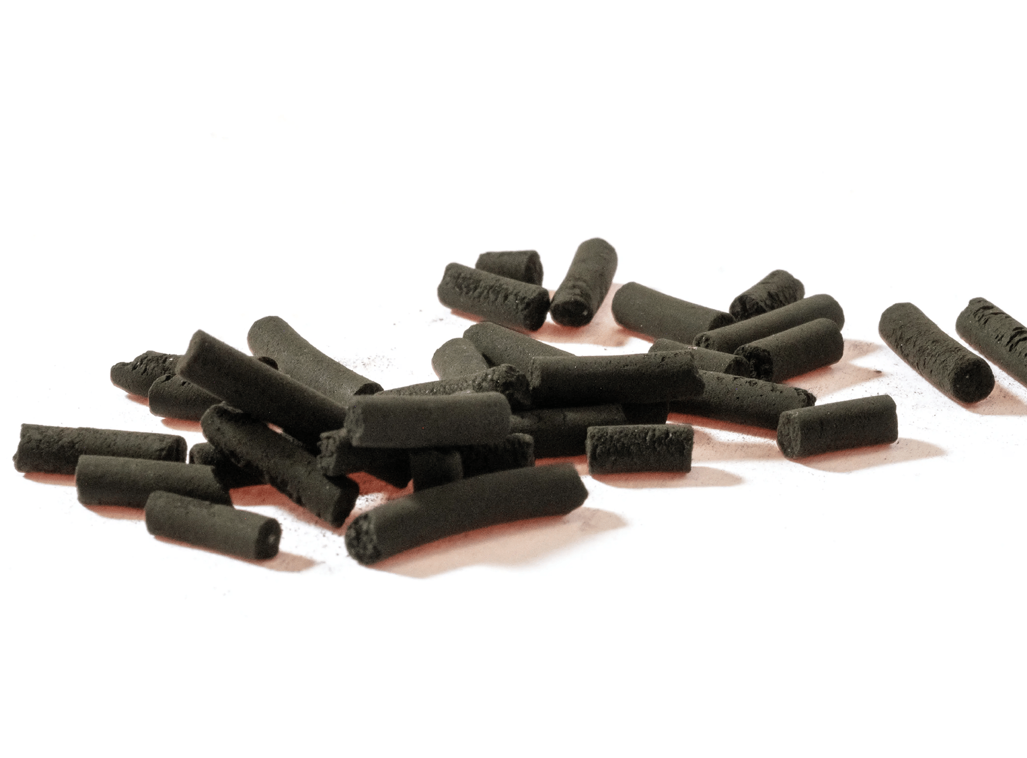 Black catalyst extrusions scattered on a white surface.