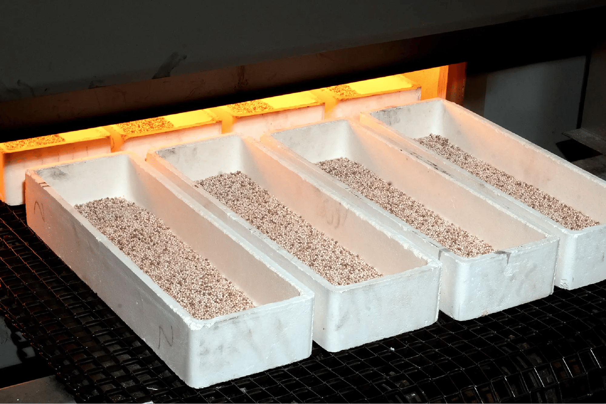 Custom manufacturing catalyst pellets in high-temperature trays during an industrial heat treatment process.