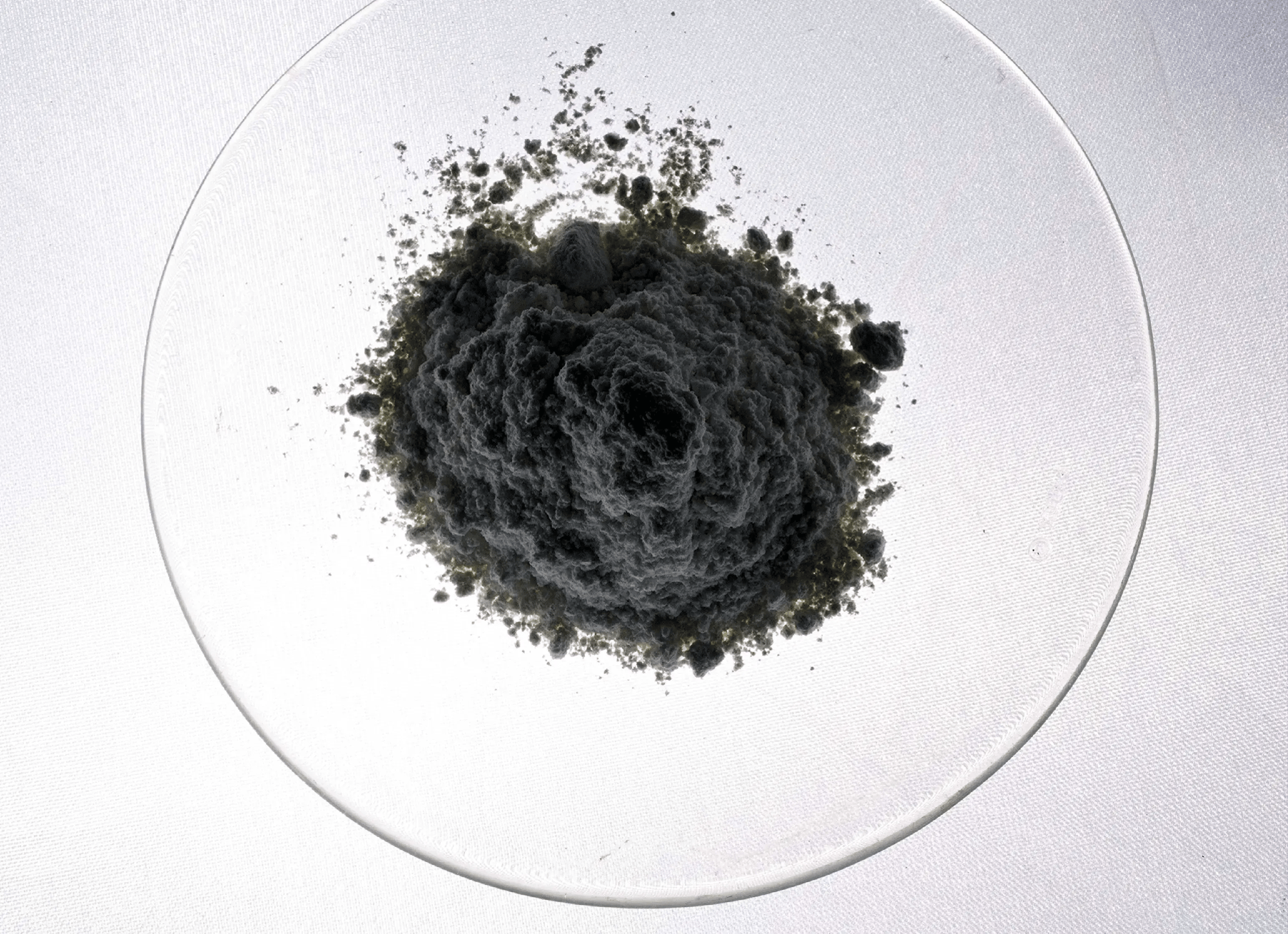 Dark slurry catalyst powder in a glass dish used for catalyst development and manufacturing at ActiveSite Technology.
