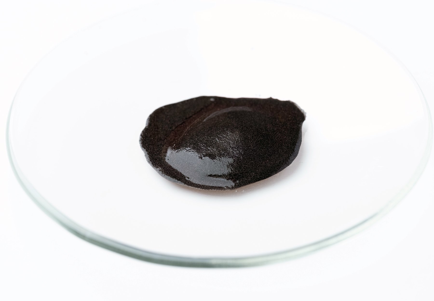 Dark slurry catalyst sample displayed in a glass dish for catalyst development and testing at ActiveSite Technology.