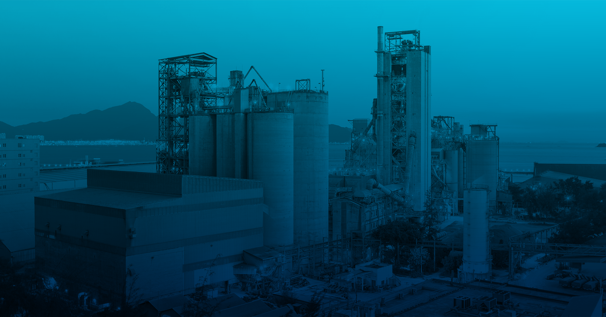 Industrial manufacturing facility with processing towers and storage silos, shown with a blue overlay to represent advanced industrial technology and innovation.